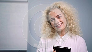 Portrait of smiling attractive businesswoman wearing white classic shirt holding notepad