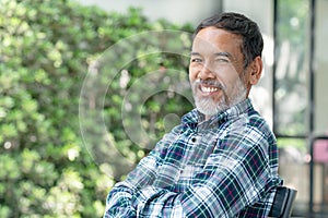 Portrait smiling attractive mature asian man retired with stylish short beard sitting outdoor