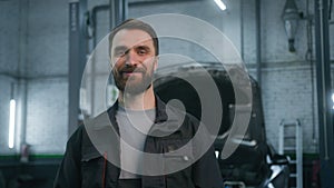 Portrait of smiling auto mechanic technical employee in work uniform looking camera at car repair service station happy