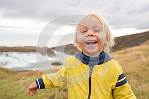 Portrait of a smiling baby boy near smaller waterfall around Gullfoss, Iceland