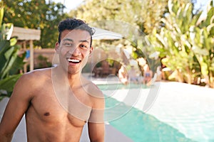 Portrait Of Smiling Bare Chested Man Outdoors With Friends At Summer Pool Party