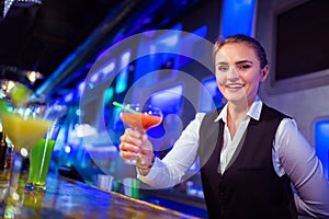 Portrait of smiling bartender holding cocktail glass