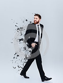 Portrait of a smiling bearded businessman in black suit walking