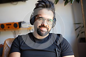 Portrait of Smiling bearded man in headphones enjoing listening to music on at home. Relaxing and rest time concept