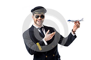 portrait of smiling bearded pilot in uniform pointing at toy plane in hand