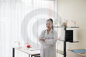 Portrait of smiling beautiful asian female doctor standing and cross arms looking something at hospital,Happy and positive thinkin