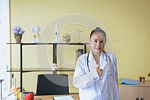 Portrait of smiling beautiful asian woman doctor showing thumps up sign at hospital,Happy and positive attitude