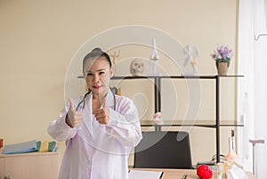 Portrait of smiling beautiful asian woman doctor showing two thumps up sign at hospital,Happy and positive attitude
