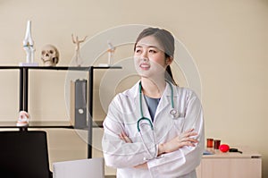 Portrait of smiling beautiful asian woman doctor standing and cross arms at hospital,Happy and positive attitude