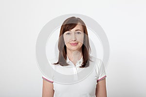 Portrait of smiling beautiful brunette woman in blank white t-shirt with copy space on white background. Mock up