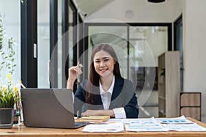 Portrait of smiling beautiful business asian woman with working in modern office desk using computer, Business people
