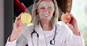 Portrait of smiling beautiful female doctor holding apple and peach fruits