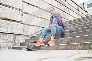 Portrait of smiling Beautiful modern young female teenager with extraordinary hairstyle color in checkered sitting on the old town