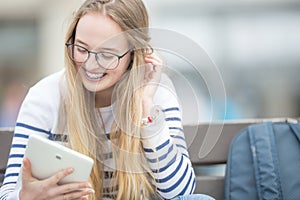 Portrait of a smiling beautiful teenage girl with dental braces. Young schoolgirl with school bag and tablet device