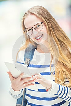 Portrait of a smiling beautiful teenage girl with dental braces. Young schoolgirl with school bag and tablet device