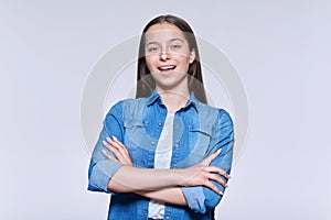 Portrait of smiling beautiful teenage girl looking at camera on light background
