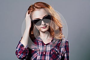 Portrait of a smiling beautiful young red-haired girl in sunglasses