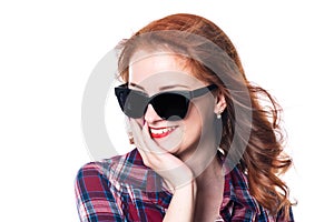 Portrait of a smiling beautiful young red-haired girl in sunglasses looking away