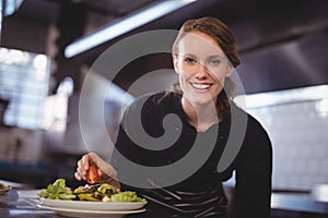 Portrait of smiling beautiful young waitress preparing salad at counter