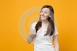 Portrait of smiling beautiful young woman in white casual clothes looking camera, showing thumb up isolated on bright
