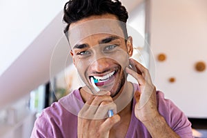 Portrait of smiling biracial man brushing teeth in bathroom