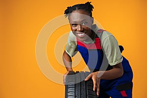 Portrait of smiling black female mechanic posing with new car tyres in studio