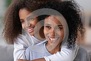 Portrait of smiling black teenage daughter piggyback young mom