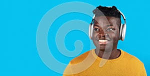 Portrait Of Smiling Black Young Man Listening Music In Wireless Headphones