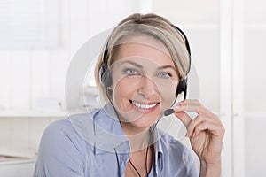 Portrait of smiling blond mature woman working with headphone.