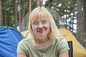 Portrait of a smiling blonde woman 30-35 years old, looking directly into the camera against the background of nature and tourist