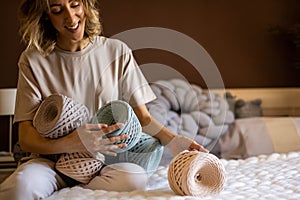 Portrait smiling blonde woman design holding pile of multicolored hank reel ribbon yarn