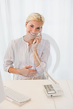Portrait smiling blonde woman using computer and phoning