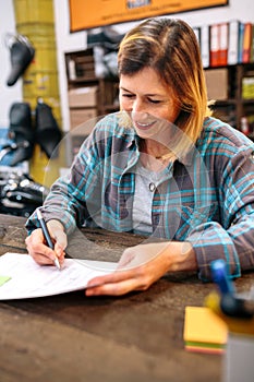 Portrait of smiling blonde young woman filling order forms for ecommerce shop