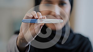 Portrait smiling blurred arabian young woman pregnant muslim girl in hijab future mother showing positive pregnancy test