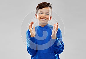 Portrait of smiling boy in blue hoodie applauding