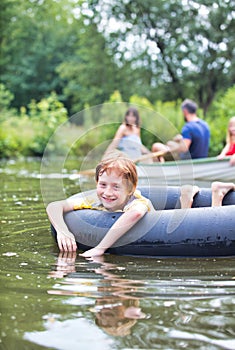 Portrait of smiling boy floating with inflatable ring in lake against family