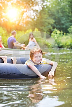 Portrait of smiling boy floating with inflatable ring in lake against family