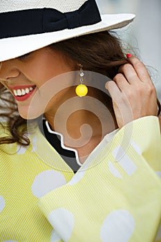 Portrait of a smiling brunette girl in a hat and yellow in white peas blues