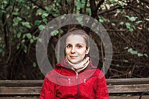 Portrait of smiling brunette in red coat in autumn park