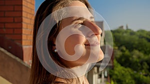 Portrait of smiling brunette woman looking on the setting sun from the balcony of her villa