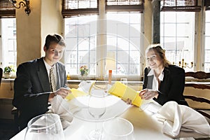 Portrait of smiling business couple with menus at restaurant table