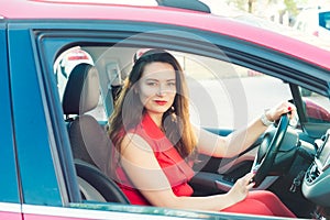 Portrait of smiling business lady, caucasian young woman driver in red summer suit looking at camera and smiling while sitting
