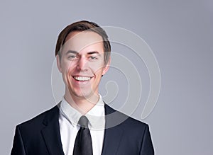 Portrait of a smiling business man in suit isolated on gray background