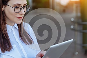Portrait of smiling business woman using tablet pc in front of office building.