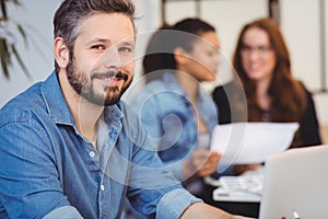 Portrait of smiling businessman against female coworkers