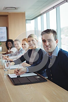 Portrait of smiling businessman with colleagues sitting at office