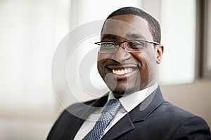 Portrait of smiling businessman in glasses, head and shoulders