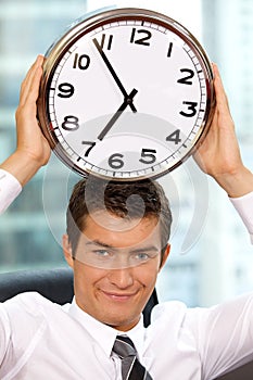 Portrait of smiling businessman holding clock to his head