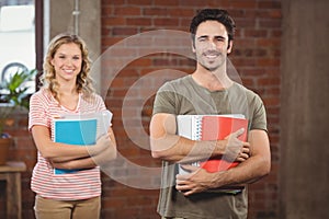 Portrait of smiling businessman holding files and folders in office