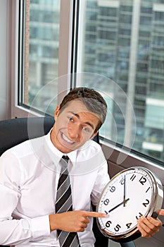 Portrait of smiling businessman pointing at a clock